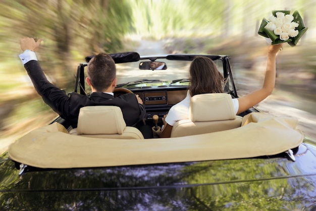 La novia y el novio conduciendo el coche de la boda