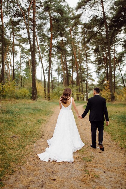 La novia y el novio corren por un bosque Sesión de fotos de boda