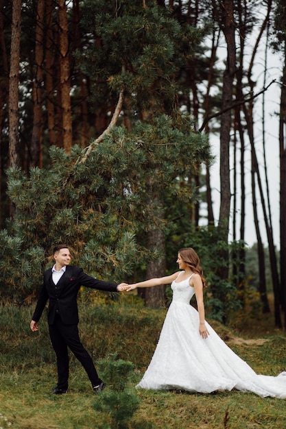 La novia y el novio corren por un bosque Sesión de fotos de boda