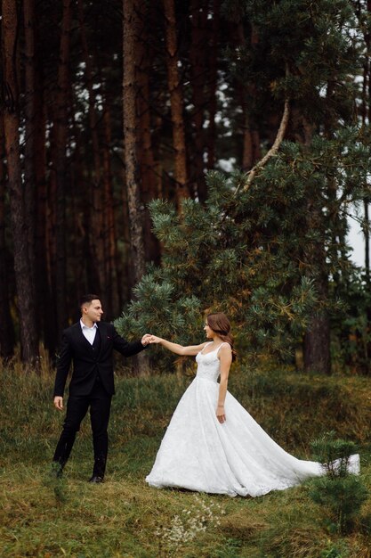 La novia y el novio corren por un bosque Sesión de fotos de boda