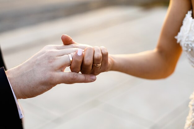 La novia y el novio se dan la mano con anillos de boda