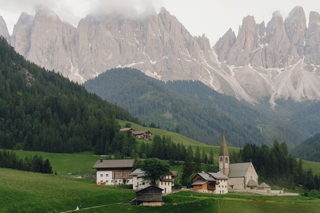 La novia y el novio se dan la mano caminando hacia la iglesia en algún lugar de los Dolomitas italianos