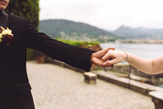 La novia y el novio se dan la mano caminando por la orilla