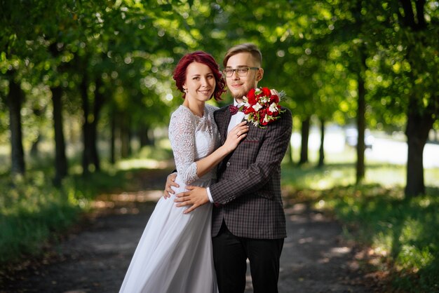 Novia y el novio en el día de la boda caminando al aire libre en la naturaleza de verano.