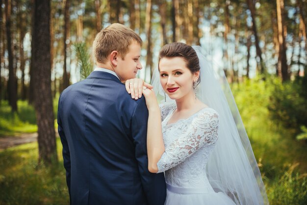 Novia y el novio en el día de la boda caminando al aire libre en la naturaleza de verano.