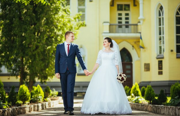 Novia y el novio en el día de la boda caminando al aire libre en la naturaleza de verano.