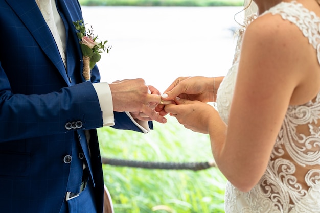 La novia y el novio intercambian anillos de boda durante el día