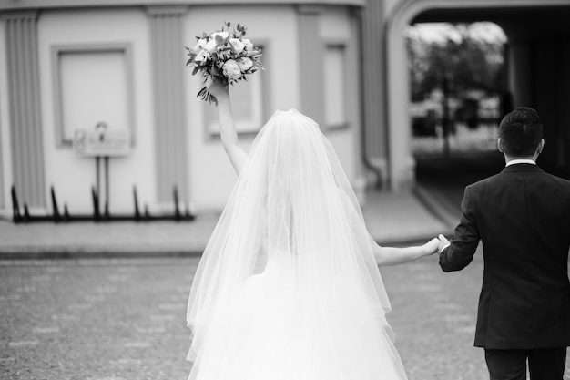 La novia y el novio mantienen sus manos juntas mientras caminan alrededor