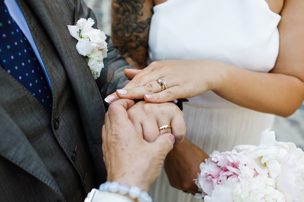 La novia y el novio muestran sus manos con anillos de boda