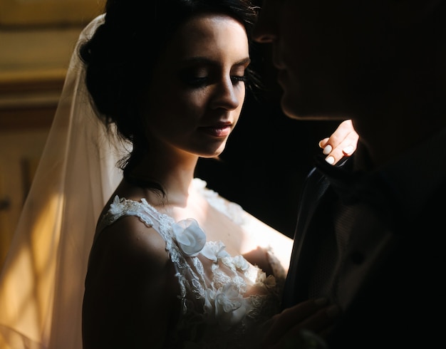 La novia y el novio posando en la habitación con poca luz