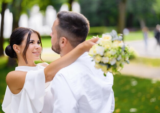 La novia y el novio posando en el jardín y sonriendo