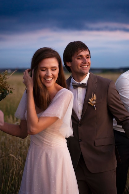 Foto gratuita novia y novio sonrientes de tiro medio al aire libre