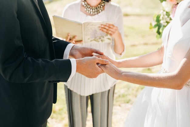 La novia y el novio sostienen sus manos juntas durante la ceremonia