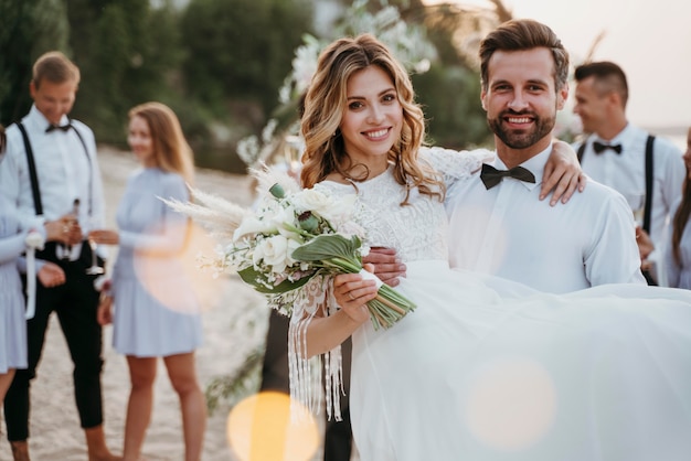La novia y el novio en su boda con invitados en la playa
