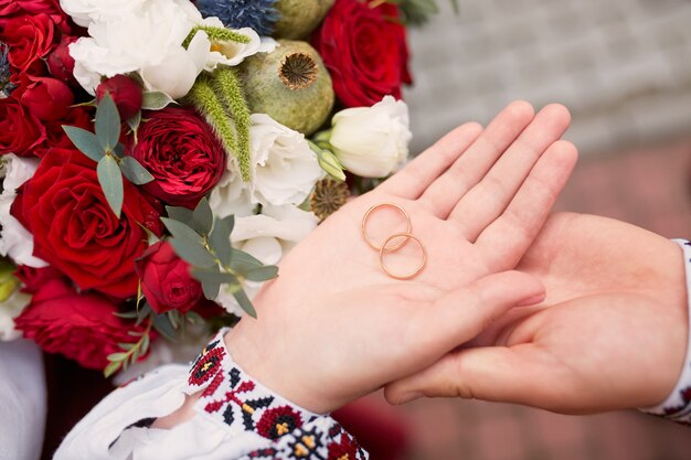 Novia y novio tienen anillos de boda en sus brazos