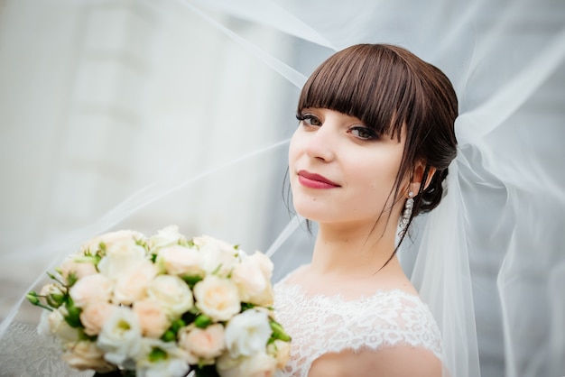 Novia con un ramo, sonriendo. Retrato de boda de la hermosa novia.