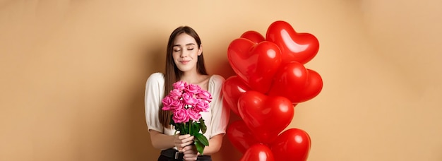 Foto gratuita la novia romántica que huele a rosas recibe flores de su amante el día de san valentín parado cerca de él rojo