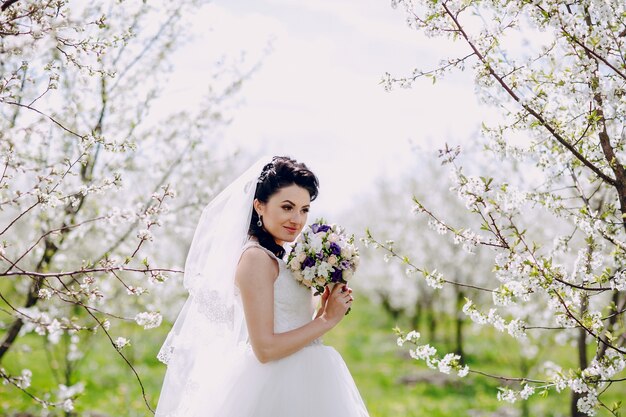 Novia sonriente posando con árboles en flor