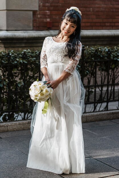 Novia sonriente posando en la calle con ramo