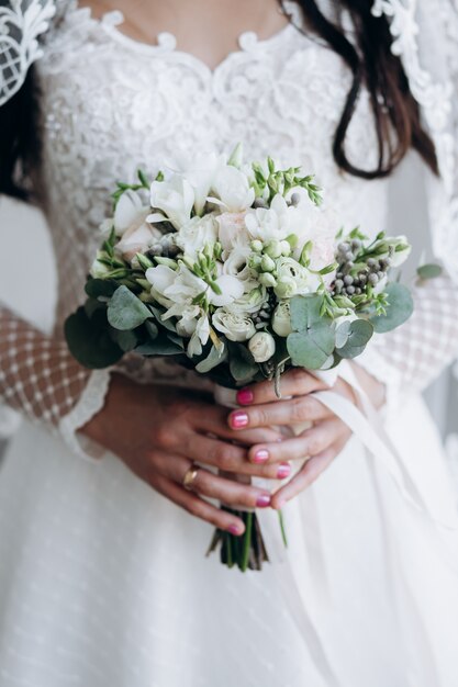 La novia sostiene un hermoso ramo de flores blancas y eucalipto.