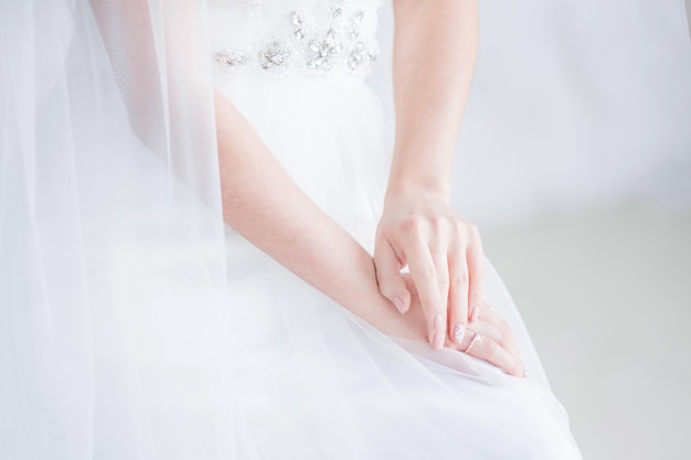 La novia sostiene sus manos cruzadas sobre las rodillas