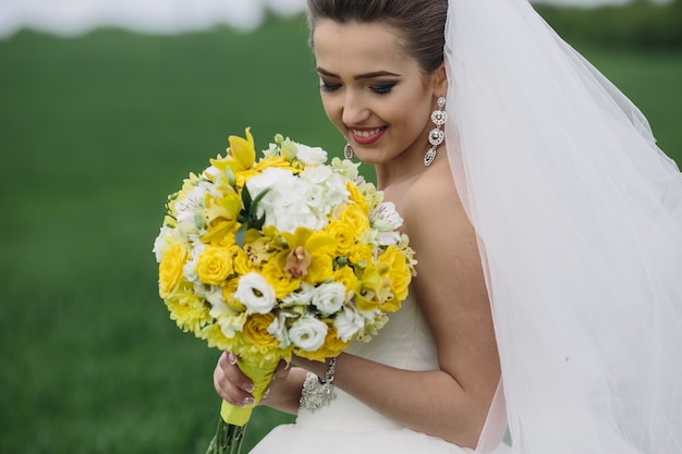 Novia sujetando su bonito ramo de flores al aire libre