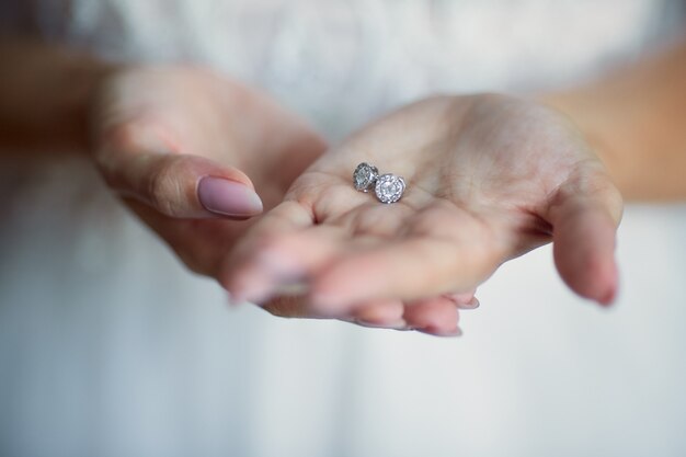 La novia tiene pendientes de plata en sus brazos.