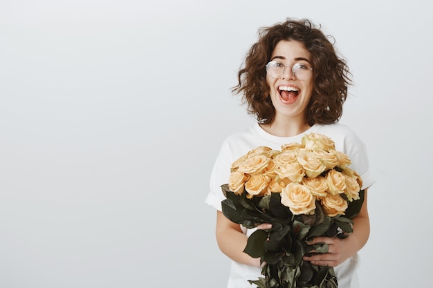 Novia tierna feliz recibe ramo de flores hermosas, sosteniendo rosas y suspirando asombrado