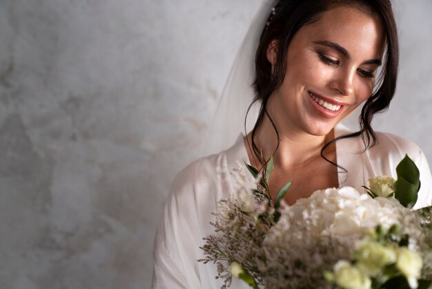 Novia de tiro medio posando con flores.