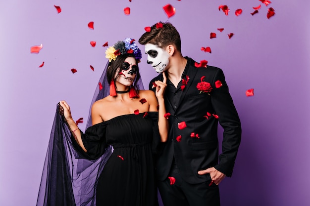 Foto gratuita novia vampiro inspirada posando en vestido negro. pareja muerta celebrando la boda en halloween.
