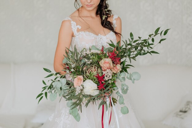 novia en un vestido blanco con un lujoso ramo decorado con eucalipto