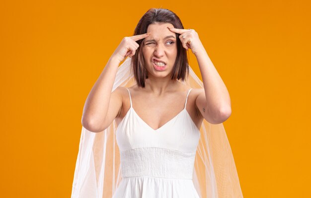 Novia en vestido de novia hermoso mirando a un lado confundido y disgustado de pie en naranja