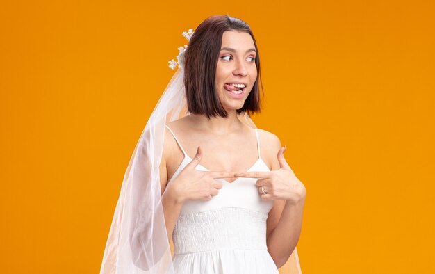 Novia en vestido de novia hermoso mirando a un lado feliz y alegre sacando la lengua