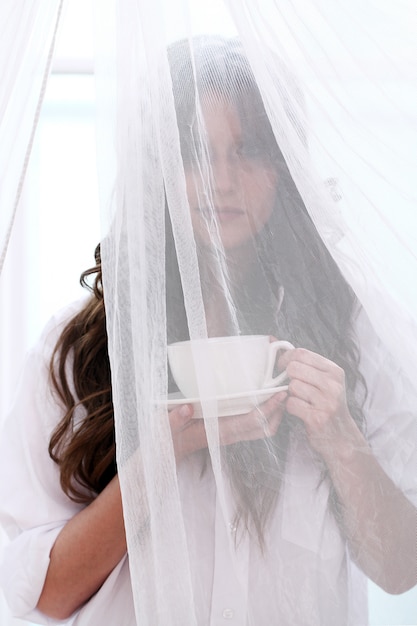 Novia en vestido de novia con una taza de bebida