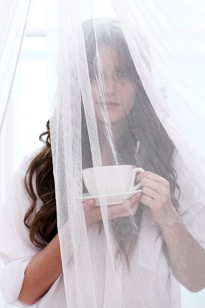 Novia en vestido de novia con una taza de bebida