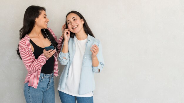 Novias alegres escuchando música en auriculares