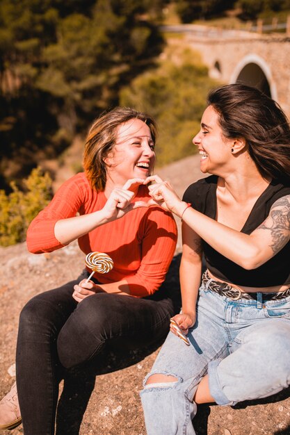 Novias alegres que muestran gesto de corazón