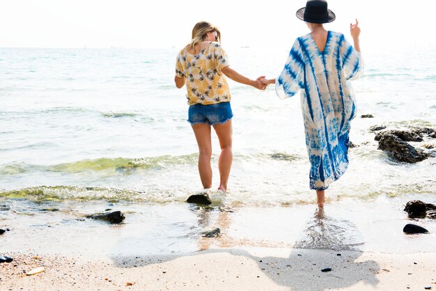 Novias cogidos de la mano y caminando en la playa