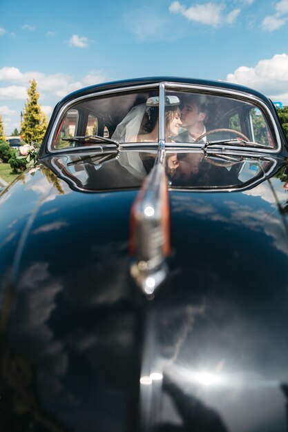 Novias felices se besan en el auto