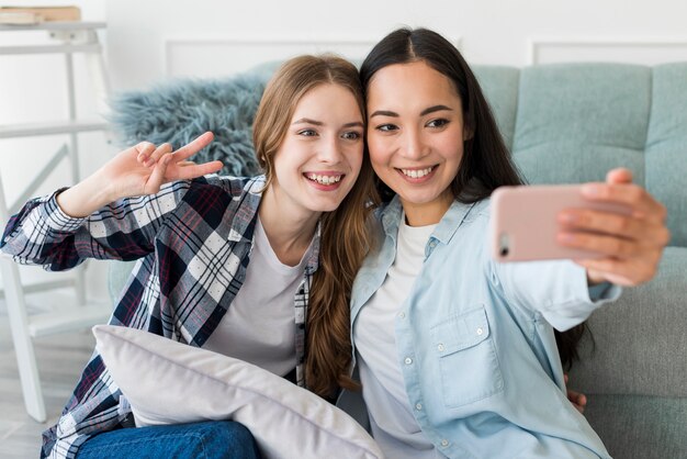 Novias jovenes alegres que toman el selfie en el teléfono móvil