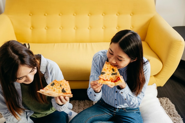 Novias jóvenes comiendo pizza en casa
