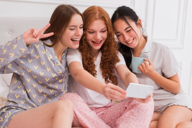 Novias juguetonas de ángulo bajo tomando selfie