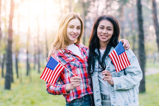 Novias con pequeñas banderas americanas de pie al aire libre