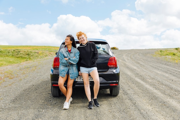 Novias de pie cerca de un coche en la carretera