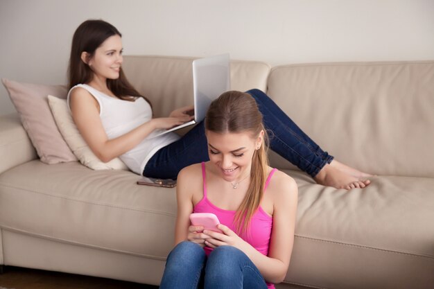 Novias que se relajan en casa con aparatos móviles