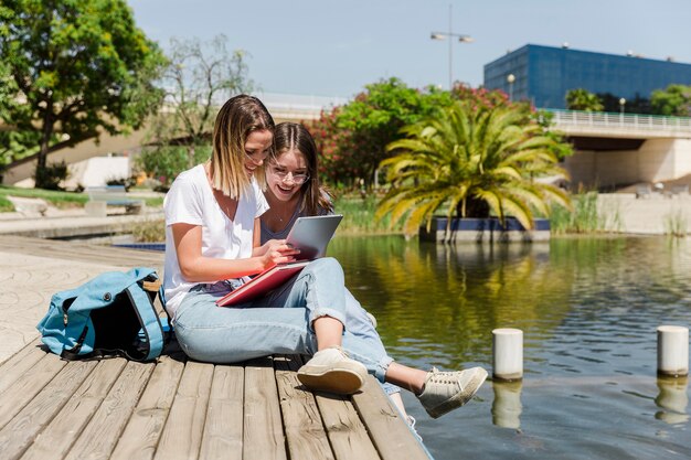 Novias con tableta en el parque con lago