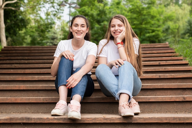 Novias de tiro largo mirando a cámara en las escaleras