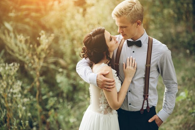 Novio abrazando suavemente a su novia en el bosque