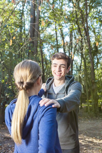 Novio adorable haciendo ejercicios de calentamiento con su novia en el bosque