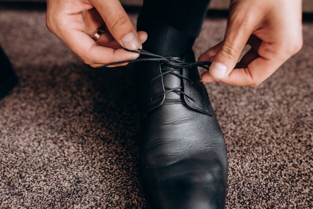 Novio ata cordones en sus zapatos sentado en un sofá